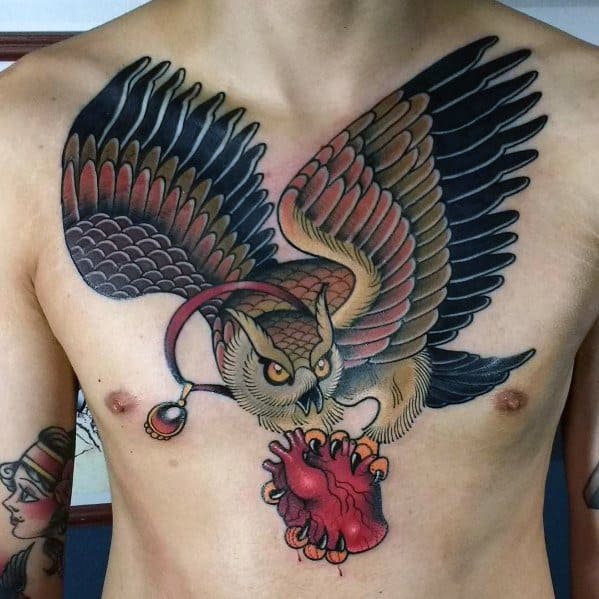 Neo-traditional owl chest tattoo with bold shading, outstretched wings, and a fierce grip on an anatomical heart, creating a striking design.