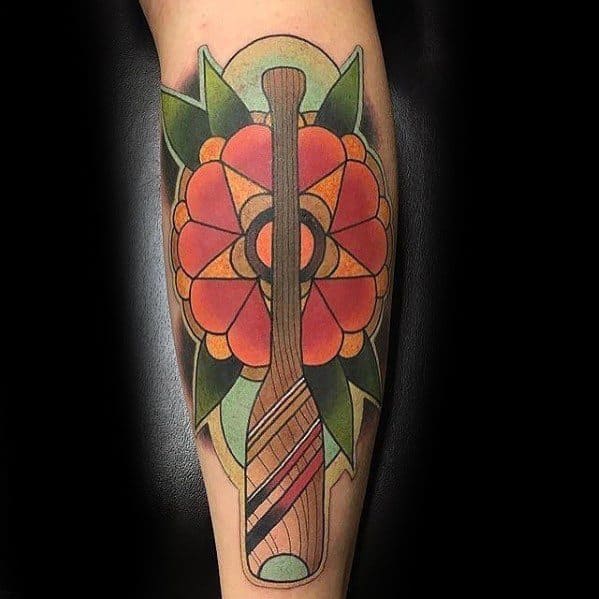 Bold traditional-style tattoo featuring a wooden paddle over a vibrant geometric flower, symbolizing adventure, nature, and a love for paddling.