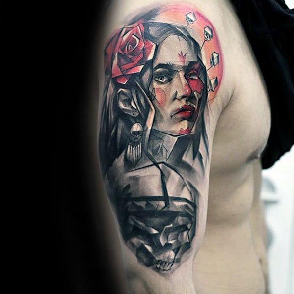 Tattoo on upper arm featuring a woman's face with red accents, geometric shapes, a rose, and skull details