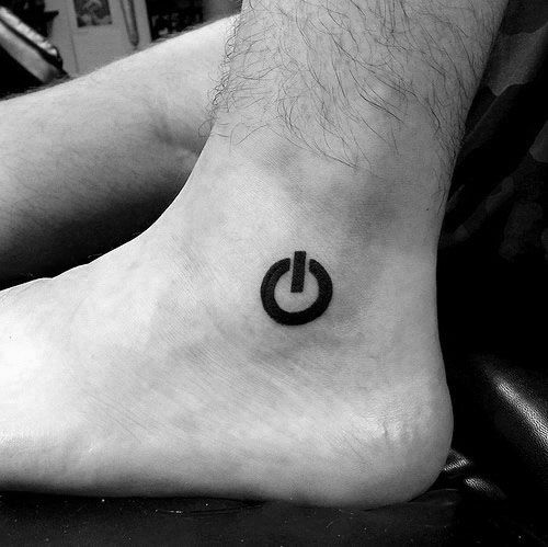 Simple black power symbol tattoo placed on the inner ankle, showcasing a clean and minimalist design.