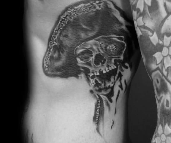 Black and gray tattoo of One-Eyed Willy from The Goonies, featuring a detailed skull wearing a pirate hat with realistic shading.