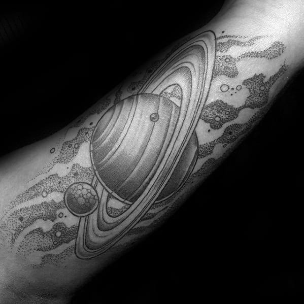 Detailed Saturn tattoo design for men featuring bold rings, surrounding moons, and a textured space background in fine black shading.
