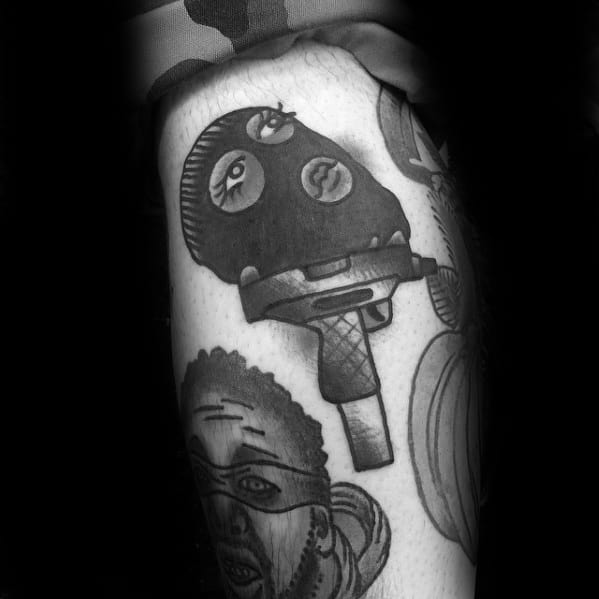 Tattoo of a ski mask with feminine eyes and lips, placed on the blade of a knife, surrounded by other stylized portrait tattoos.
