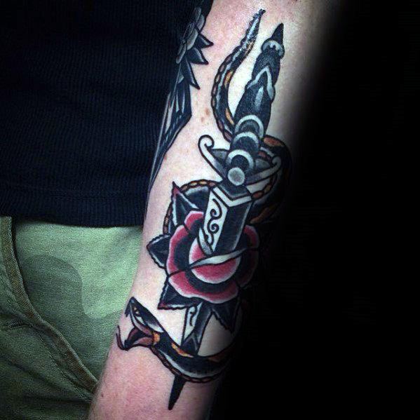Traditional snake and dagger tattoo on forearm, featuring a bold black and red rose with intricate shading and classic design elements.