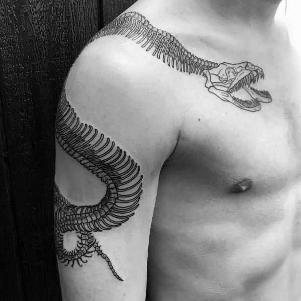 Snake skeleton tattoo wrapping around the shoulder and arm, featuring a detailed skull and ribcage for a bold and dynamic design.