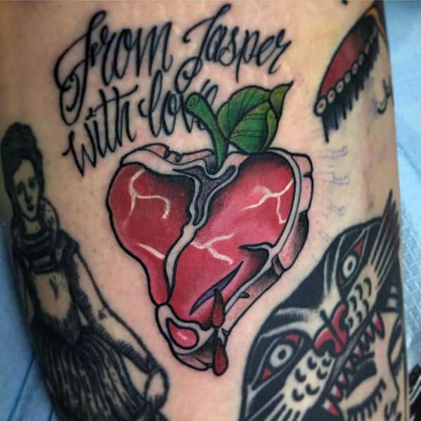 Tattoo of a heart-shaped steak with a green leaf on top, resembling an apple, with bold shading and dripping details, featuring the text from Jasper with love