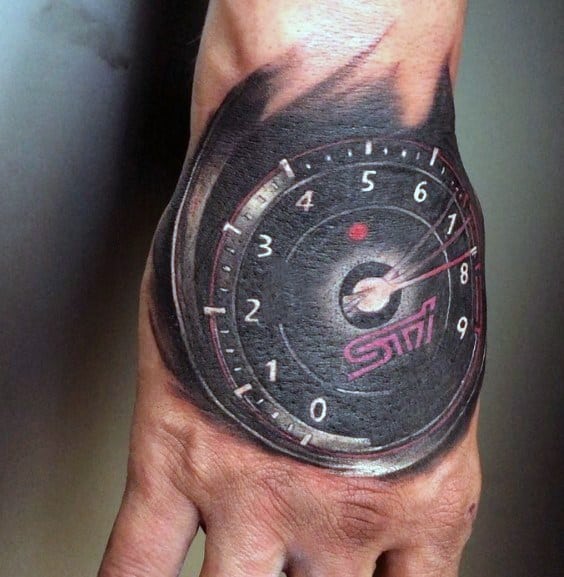 Realistic Subaru STI tachometer tattoo on the hand, featuring a detailed gauge design with a redline effect and the iconic STI logo.