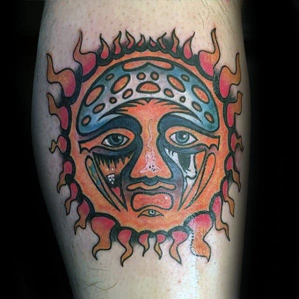 Bright and bold Sublime sun face tattoo with red and orange flames, blue accents, and detailed facial features on the calf.