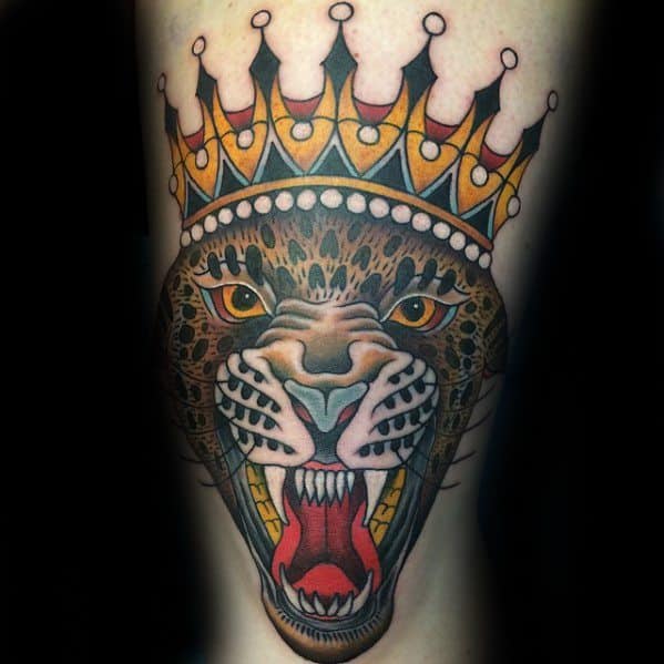 Bold traditional tattoo of a crowned roaring leopard with vivid yellow eyes, sharp teeth, and rich colors on the upper arm.