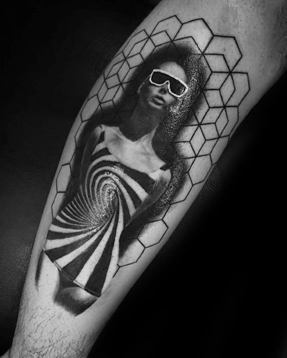 Black and grey tattoo of a woman in a hypnotic spiral dress with sunglasses, framed by geometric hexagonal outlines on the leg.