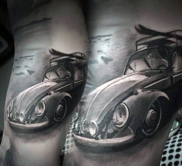 Black and gray tattoo of a classic Volkswagen Beetle with a surfboard on top, set against a coastal background on the arm.