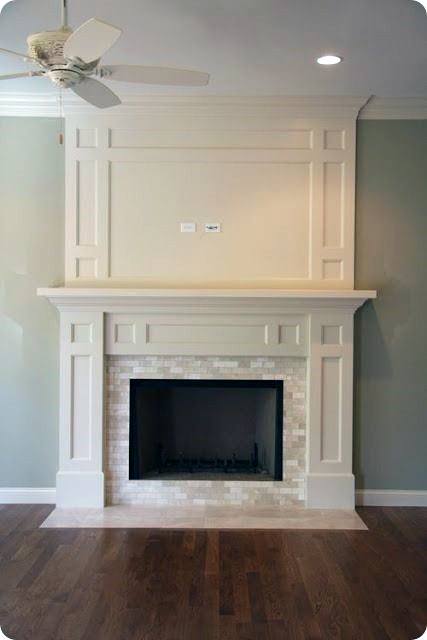 The fireplace features a white mantel with decorative paneling and a tiled surround, framing a dark firebox.