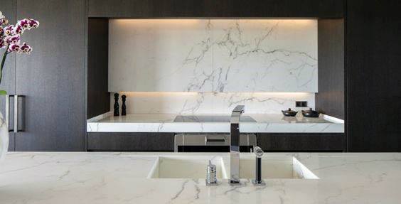 Modern kitchen with marble backsplash, integrated sink, and dark wood cabinetry.