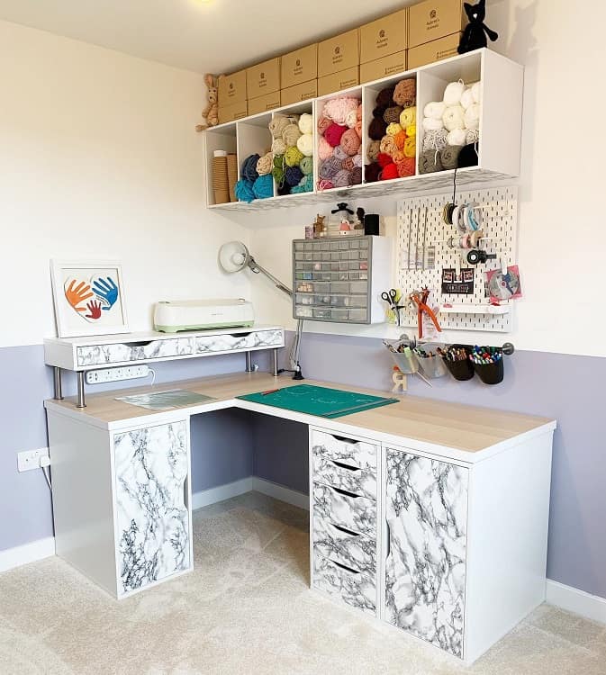 Craft room with a marble desk, yarn shelves, a pegboard with tools, and a colorful handprint artwork