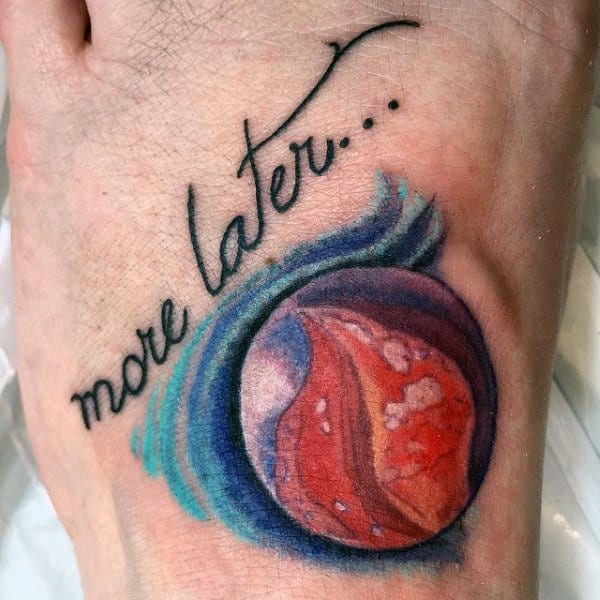 Colorful tattoo of a red marble with a swirling blue design and the phrase "more later..." in cursive, symbolizing nostalgia and unfinished stories.