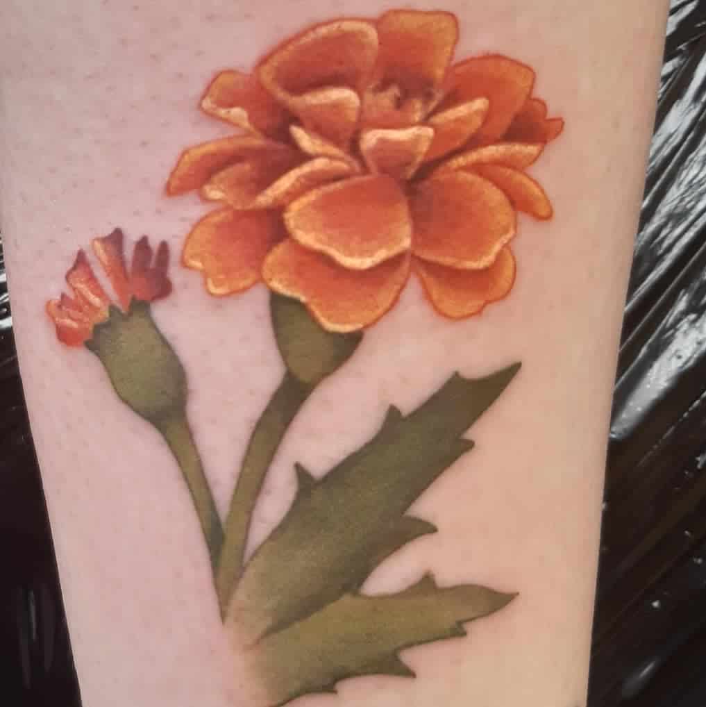 A vibrant orange marigold tattoo with a closed bud and green leaves