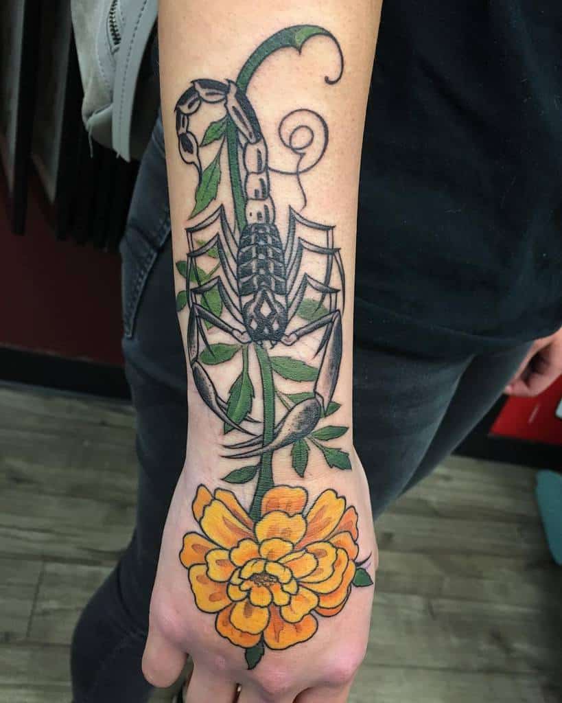 Tattoo featuring a bold black scorpion entwined with green vines, ending in a vibrant orange marigold