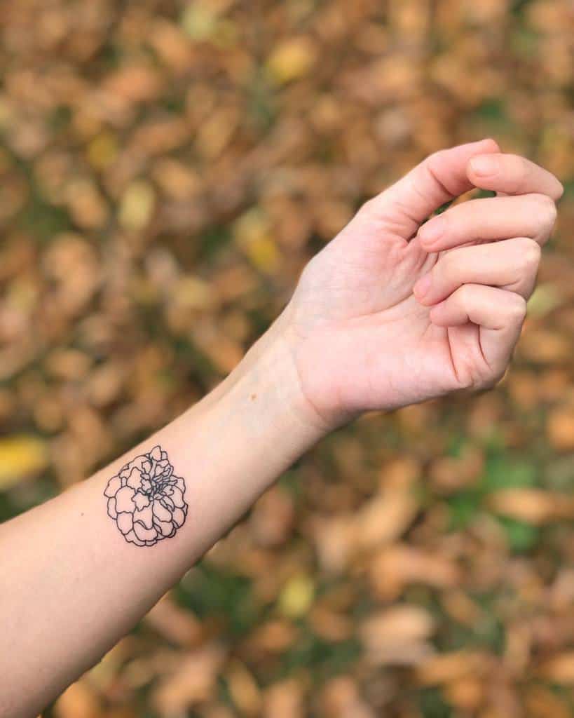 A hand with a delicate marigold tattoo in black inked