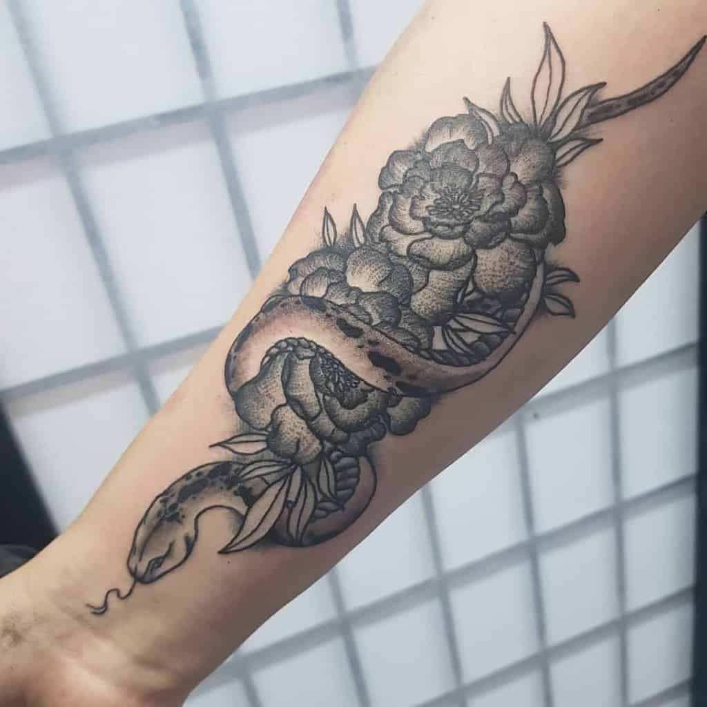 Black and grey tattoo featuring a detailed snake entwined with blooming marigolds, with intricate shading and fine dot work