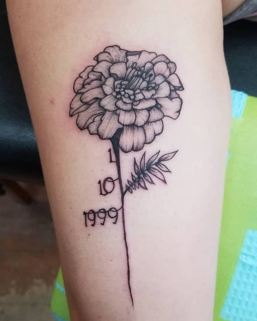 Black and grey marigold tattoo with fine shading, featuring a stem that transforms into a timeline with the numbers '1', '10', and '1999'