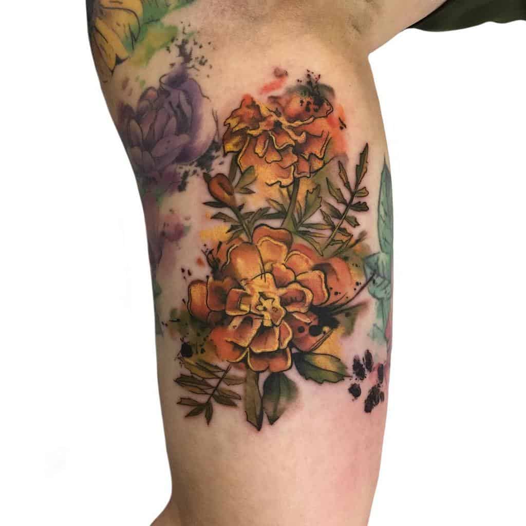 Vibrant watercolor-style tattoo featuring bold orange marigolds with expressive splashes of color, fine botanical details