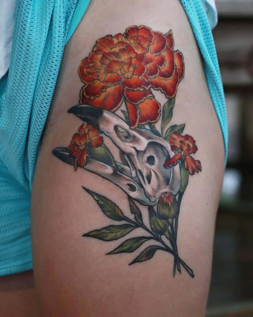 Bold tattoo featuring vibrant orange marigolds intertwined with a detailed animal skull, blending nature and gothic elements