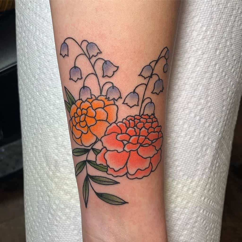 Tattoo of orange marigold flowers with green leaves and purple bell-like flowers
