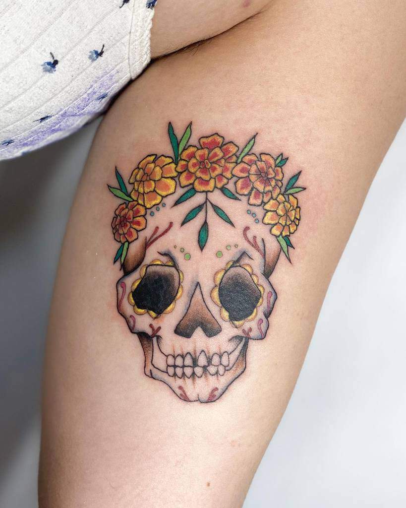 Colorful sugar skull tattoo adorned with bright orange marigold flowers, inspired by Día de los Muertos