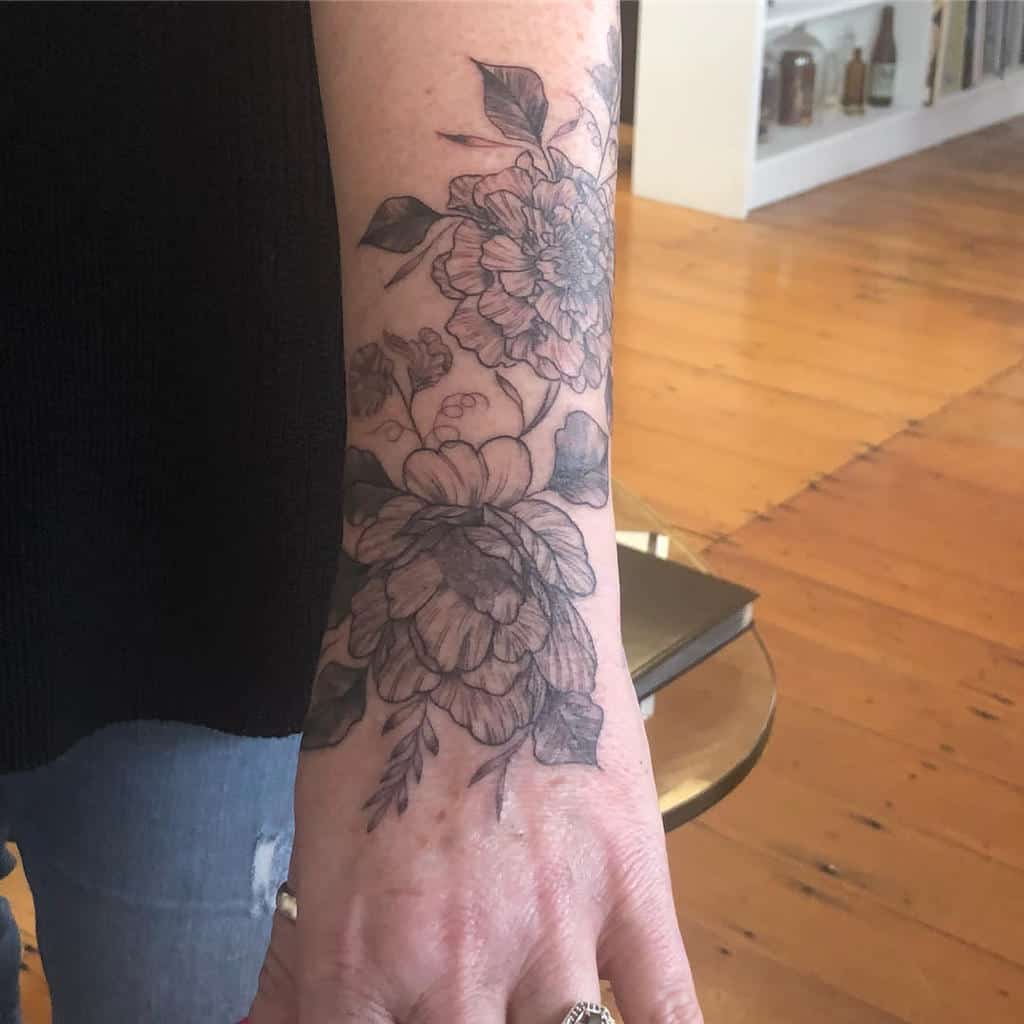 Black and gray floral tattoo featuring detailed marigold blossoms and leaves