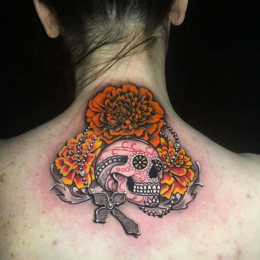 Bold tattoo featuring a Día de los Muertos sugar skull, vibrant orange marigolds, a rosary, and a stone cross in rich detail