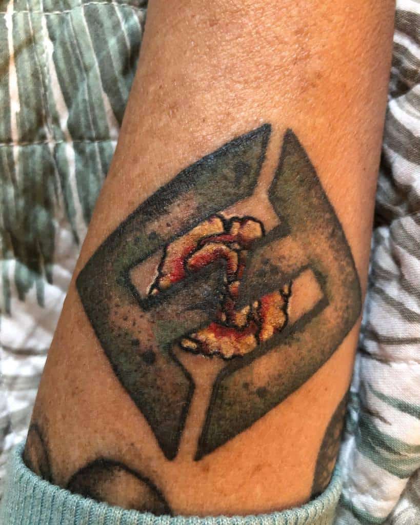 Geometric tattoo with a marigold flower at the center, blending bold black shapes with vibrant orange and yellow floral details