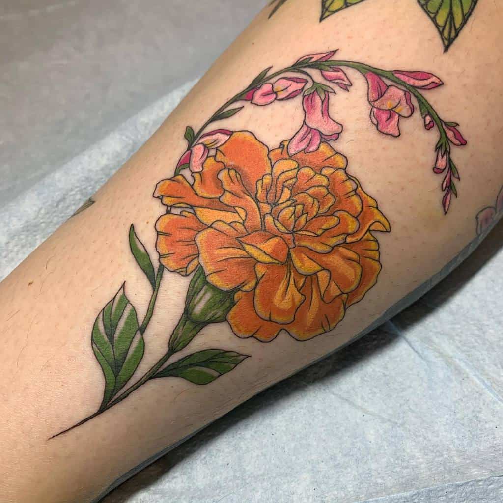Tattoo of a vibrant orange marigold with green leaves and pink flower accents