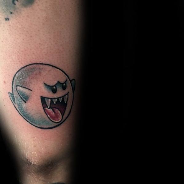 Mario ghost tattoo featuring Boo with a mischievous grin and tongue out, shaded in black and grey, inked on the arm near the elbow.