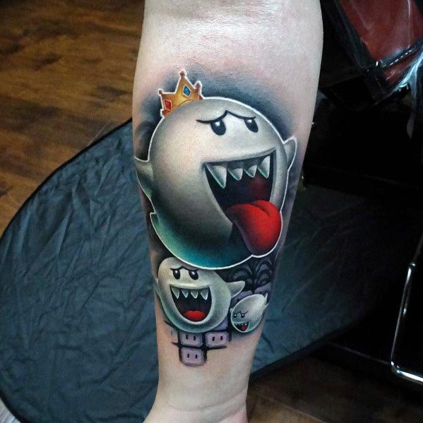 Mario ghost tattoo featuring King Boo with a golden crown, tongue out, and multiple Boos below, inked in bold colors with detailed shading.