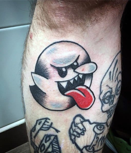 Mario ghost tattoo featuring Boo with an exaggerated nose, fierce expression, and tongue out, inked with bold black shading and red accents.