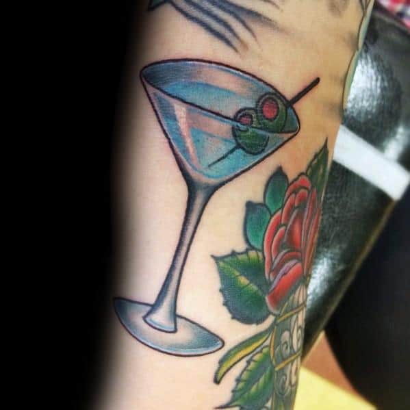 Classic martini glass tattoo with an olive garnish, paired with a vibrant red rose. A bold and timeless design with rich colors and clean lines.