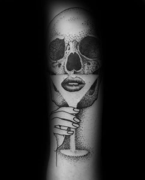 Black and grey dotwork martini glass tattoo blending a skull and lips in a surreal design. A bold, artistic concept with intricate shading.