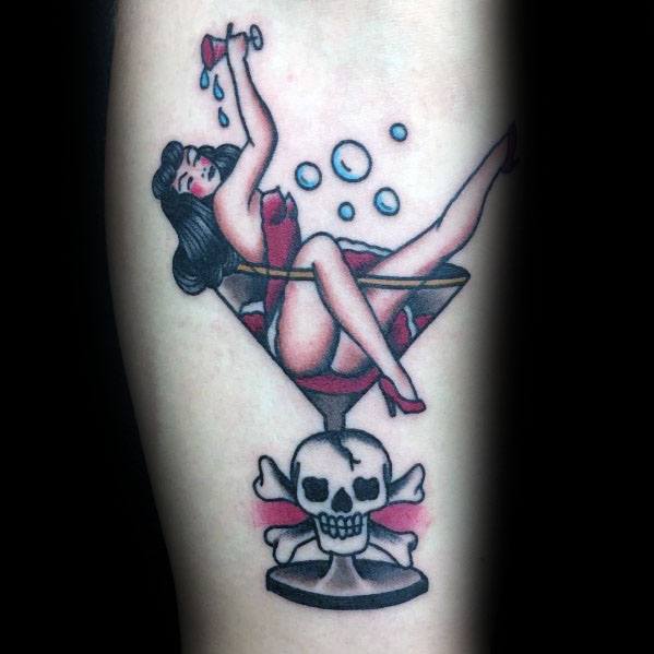Traditional-style martini glass tattoo featuring a pin-up girl lounging inside, with a skull base. A bold, vintage design with classic tattoo elements.