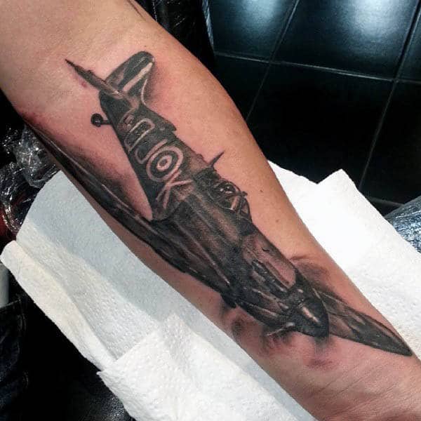Forearm tattoo of a detailed, black and grey WWII airplane soaring in flight