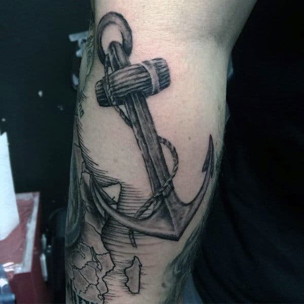 Tattoo of a large, intricate anchor with a rope elegantly wrapped around it on a person's inner forearm