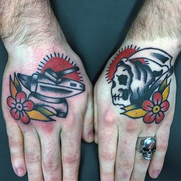 Traditional hand tattoos featuring an anvil and hammer with flowers on one hand, and a grim reaper skull with similar floral elements on the other.