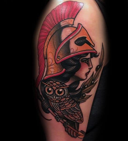 Neo-traditional Athena tattoo with bold black outlines, red helmet, olive branch, and stylized owl on upper arm