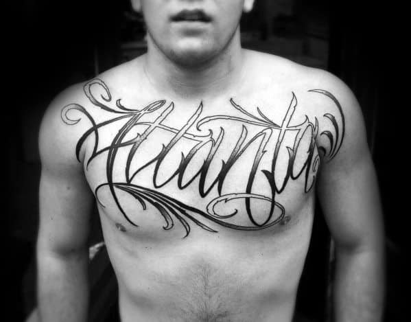 Large chest tattoo with elegant script lettering spelling Atlanta, featuring bold lines and decorative swirls across the upper chest.