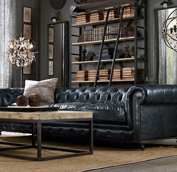 Luxurious living room with a black leather couch, wooden coffee table, bookshelves, and decorative chandeliers