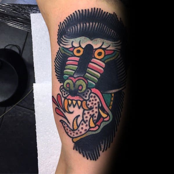 Traditional-style baboon tattoo with bold outlines, vibrant colors, and a fierce expression, featuring a snake for a striking and dynamic design.