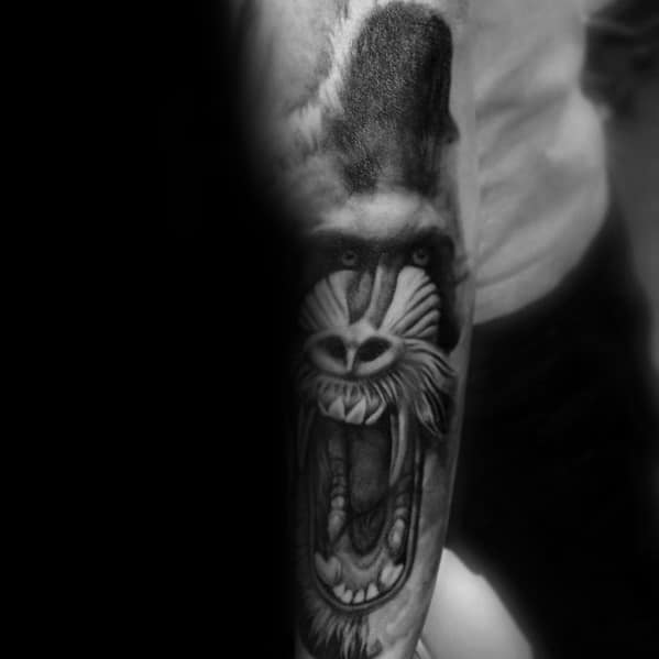 Black and grey realistic baboon tattoo with intense shading, fierce open-mouthed expression, and striking depth for a bold forearm design.