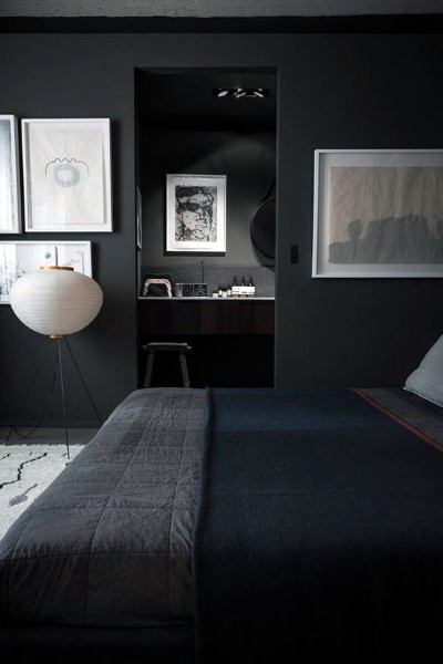 Sophisticated black bedroom with modern art, cozy bedding, and soft lighting accents.