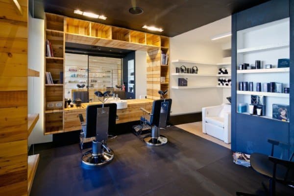 Modern barbershop with sleek black chairs, wooden shelving, and contemporary decor.