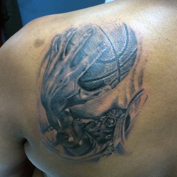 Black and gray tattoo of a hand gripping a basketball on the upper back