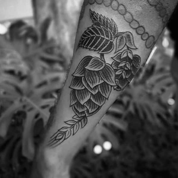 Bold blackwork tattoo of a hop plant with layered leaves and barley stem, symbolizing craft beer culture and botanical beauty.